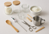 DIY A tidy workspace with jars, soy wax flakes, thermometer, and tools neatly arranged on a covered table.